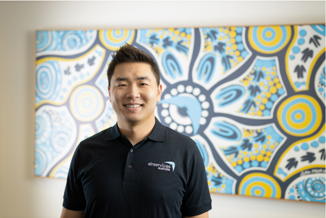 Male team member in front of First Nations artwork.