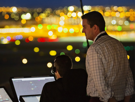 Two Melbourne air traffic controllers in Air Traffic Control Tower at night-time.