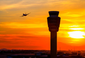 Aeroplane in the sky next to Air Traffic Control Tower.