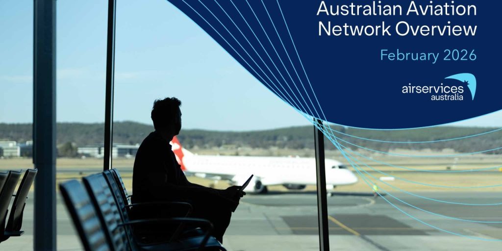 A man overlooks an airport runway and a stationary plane against a blue backdrop