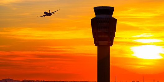 Aeroplane in the sky next to Air Traffic Control Tower.